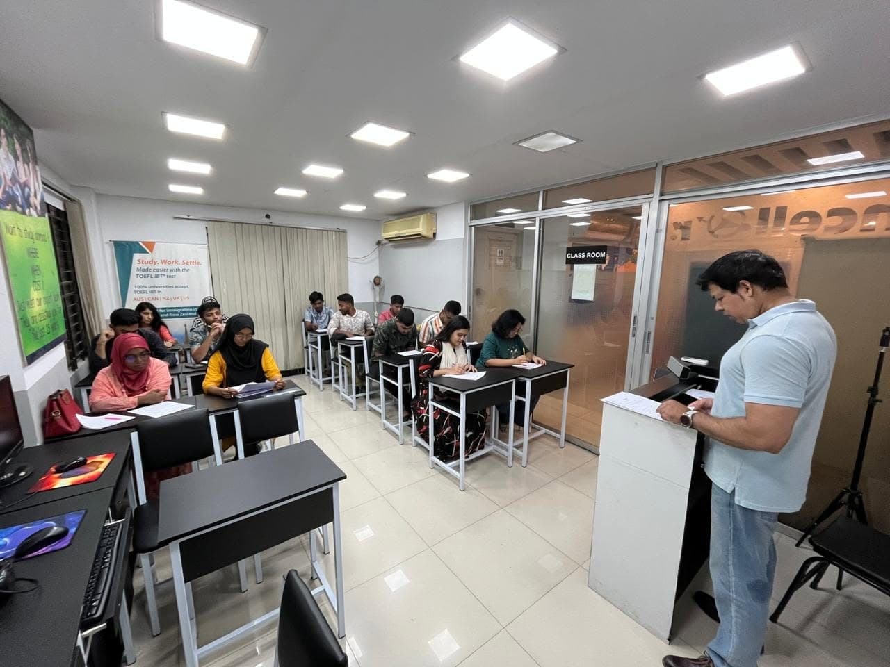 An IELTS class at Chancellor Global Education: a teacher at the lectern and students working at their desks.