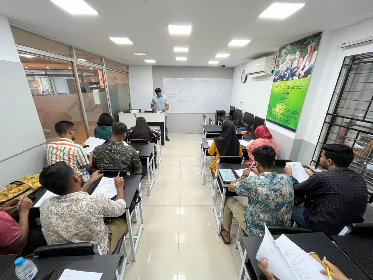 A teacher at the whiteboard while students work at their desks in a classroom at Chancellor Global Education.