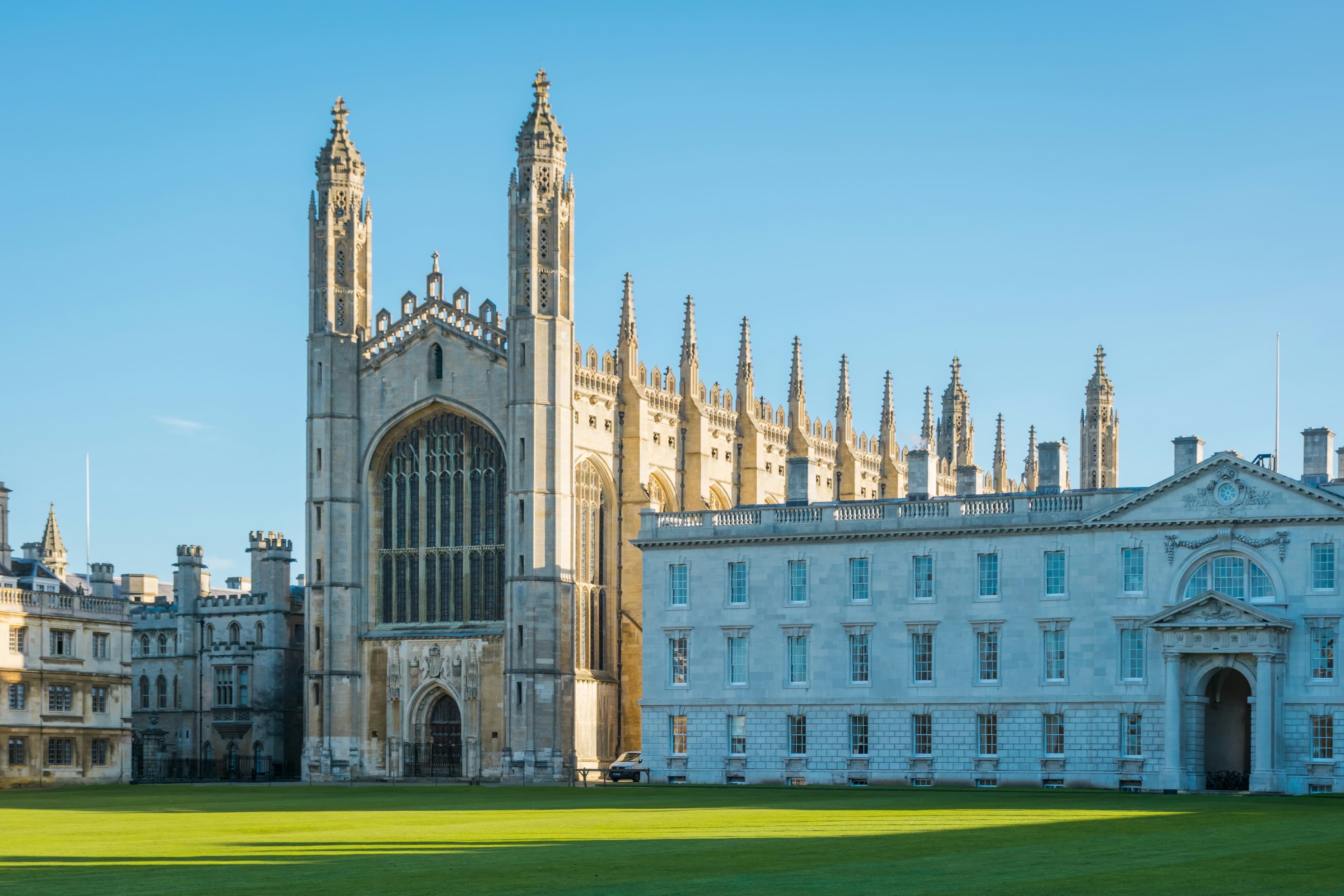 Historic university buildings overlooking a green courtyard under a blue sky.